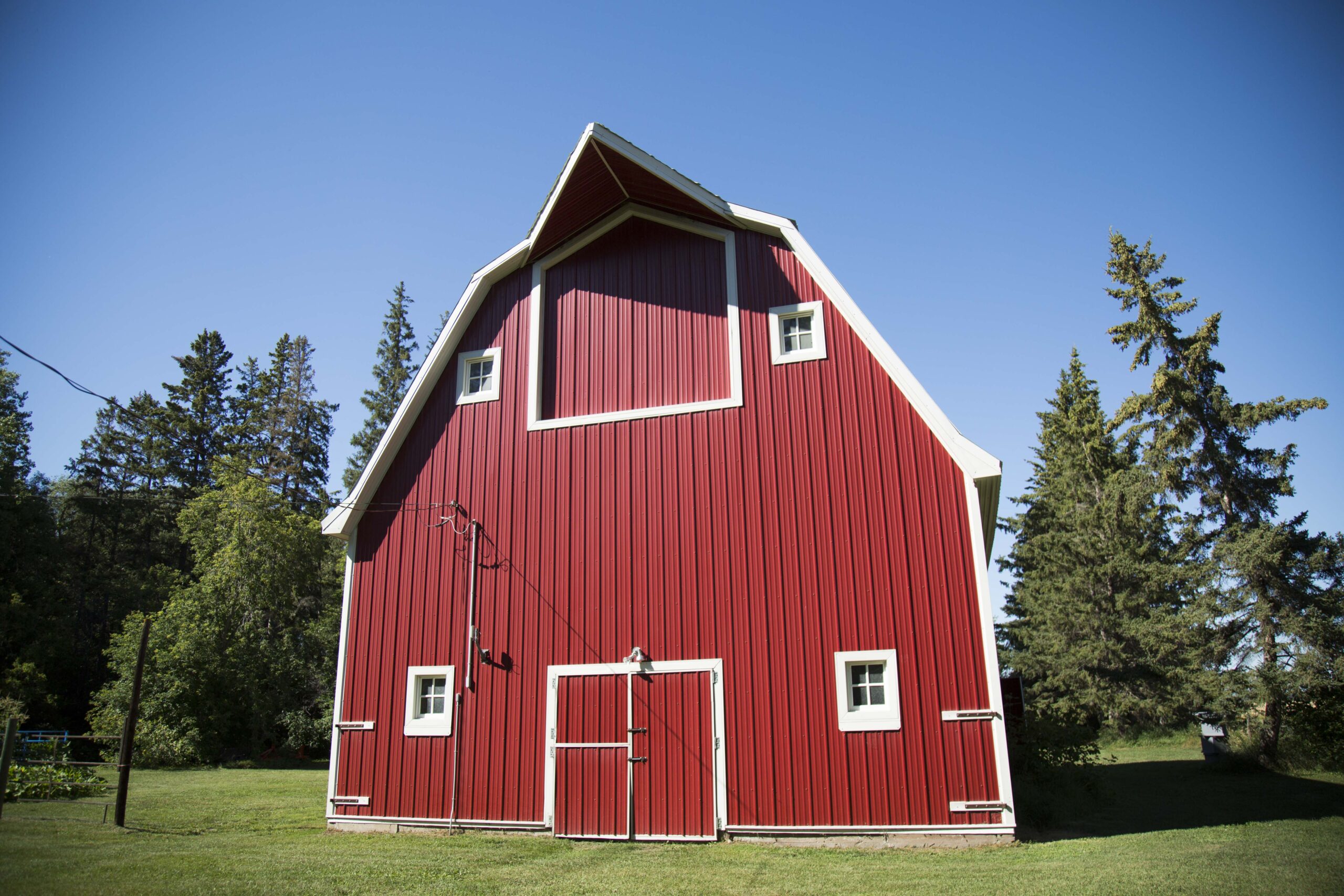 A red barn with white trim stands prominently against a clear blue sky.